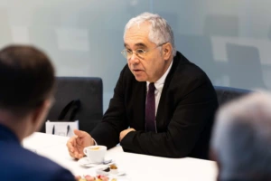 man with glasses and grey hair sitting at a table in a meeting